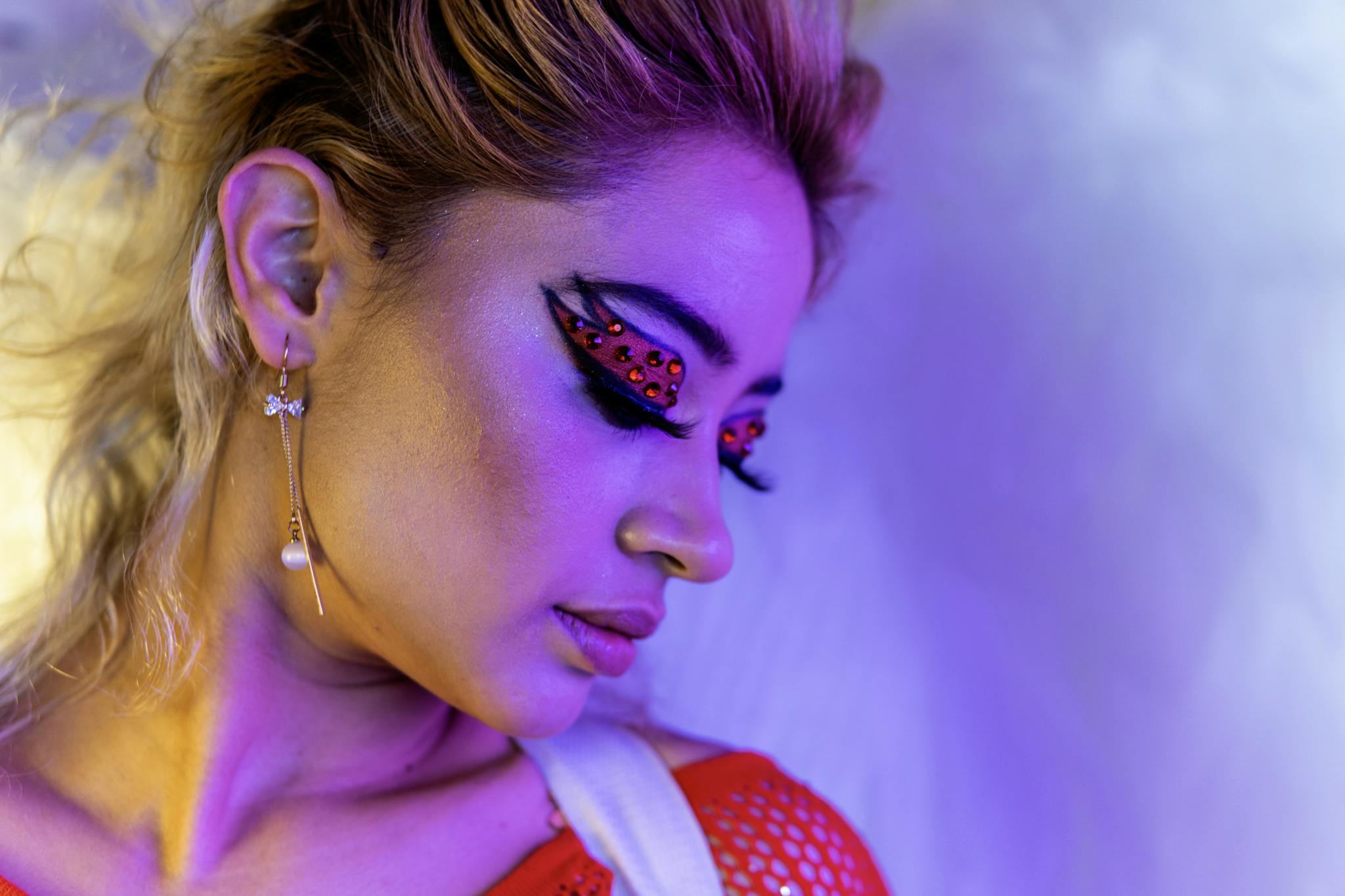 Close-up portrait showcasing vibrant makeup artistry with unique earring.