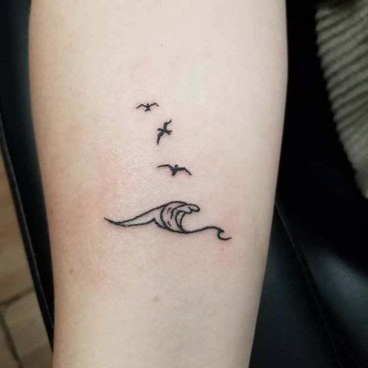 Minimalist ocean wave and three flying seagull birds tattoo design, showcasing a cute arm tattoo for women in a delicate, fine-line style.
