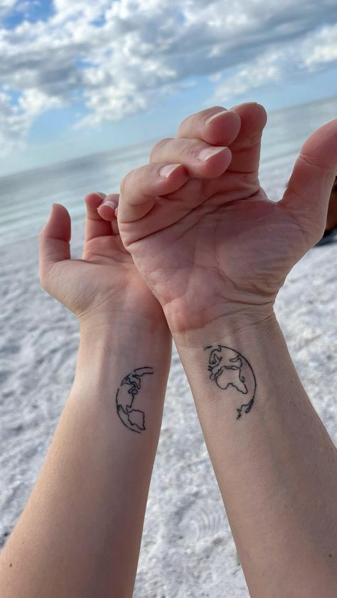 Two pair arms with matching globe tattoos