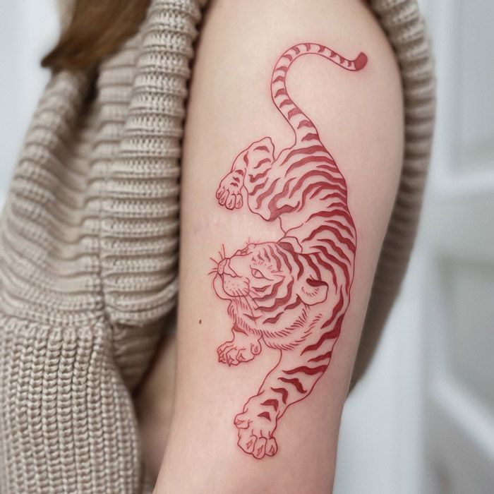Striking red outline tiger tattoo design, perfectly placed on the upper arm's tricep area. An excellent example of Animal Tattoos for the Back of the Arm, highly relevant for the focus keyword: Tattoos for the Back of the Arm."