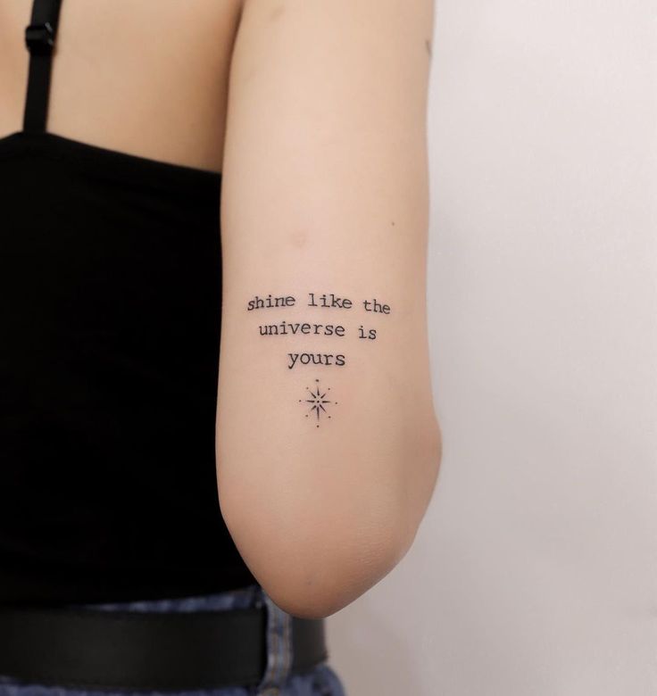 Shine like the universe is yours" script quote tattoo with a small starburst design, elegantly placed as one of many beautiful Script and Quote Tattoos for the Back of the Arm.